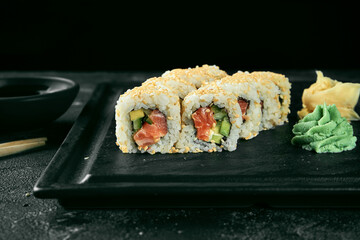 Uramaki sushi california roll in sesame with salmon, avocado and cucumber. Classic Japanese cuisine. Food delivery.