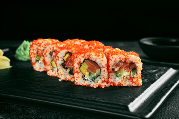 Uramaki sushi california roll in tobiko caviar with salmon, avocado and cucumber. Classic Japanese cuisine. Food delivery.