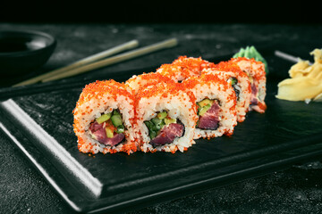 Uramaki sushi california roll in tobiko caviar with tuna, avocado and cucumber. Classic Japanese cuisine. Food delivery. Isolated on white.