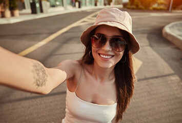 Happy hipster woman in sunglasses taking selfie in city
