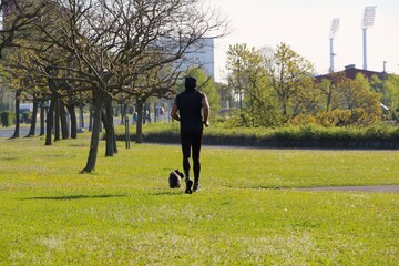 A man jogging early morning  with a small dog in Las Llamas park Sardinero Santander Cantabria Spain Spring 2021