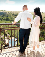 Wedding romantic couple man and woman looking on river, hills, skyline standing on brige at summer sunny day