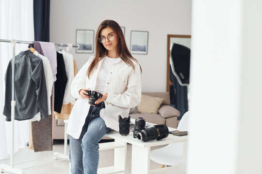 Female photographer in casual clothes is working indoors at daytime