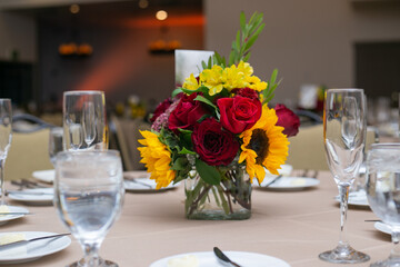 sunflowers and red flowers in small vase on a table for wedding or reception event