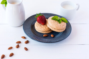 Useful Lenten cookies from almond flour with strawberry and milk on white wooden background. selective focus