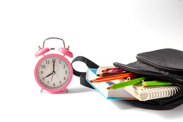 Alarm clock and open school backpack on a white background. Books, a notebook and pencils are...
