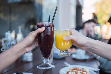 Close-up of women's hands holding fruit juices.