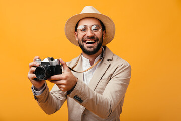 Positive man in hat and glasses holding retro camera