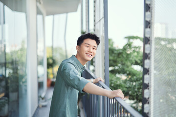 Handsome young guy is enjoying with the sun shining and trees around.