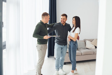 Salesman helps young couple in choosing an apartment. Conception of business and rent