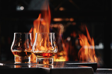 Two glasses of Scotch Whiskey on a fire background. Copy space banner. Close up