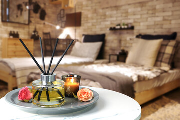 luxury aromatic scent of reed diffuser glass bottle is used as room freshener on the white marble table in the bedroom to creat relax and romantic ambient with background of nice bed on valentine day