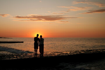 dark silhouettes of young people on the background of the sunset on the sea