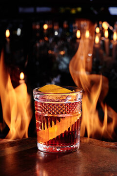 Cocktail Negroni in a beautiful glass on copper designer bar counter, the background of real fire. Series of photo. High quality photo