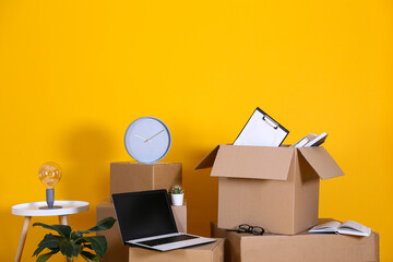 Bunch of blank moving boxes with different stuff in a new apartment. Room with freshly painted yellow walls, unpacked cardboard boxes. Interior background, copy space for text.
