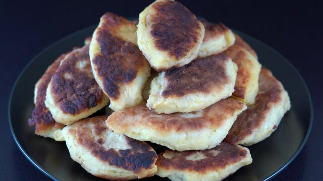 Potato cakes, ukrainian name potato zrazy, stuffed mushrooms or meat or cheese with herbs cream are fried in vegetable oil on black background, close up, rotates. Traditional Ukrainian cuisine