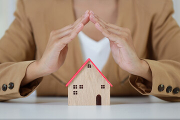 Young active business woman hands in casual dress sitting and protecting house model on white...