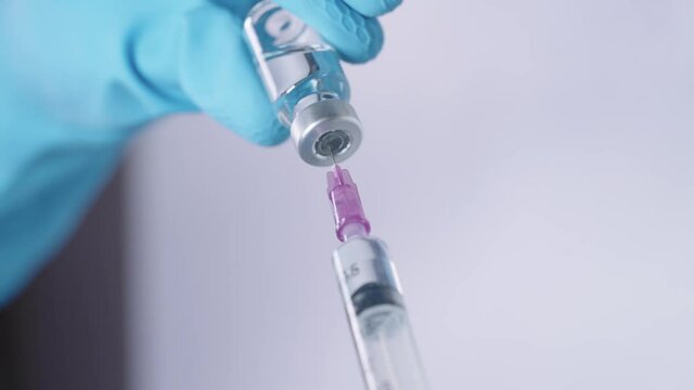 Elastic blue protective gloves filling up transparent liquid vaccine into injection needle, biotechnology inside laboratory research, outbreak epidemic, pandemic cure, get vaccinated, close up shot