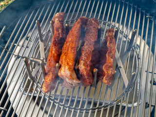 Close-up of marinated spareribs in a sparerib holder on a kettle grill during smoking.