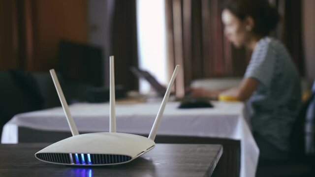 A woman is working at home using a modem router, connecting the Internet to her laptop.