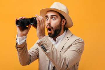 Man in hat looks surprised into binoculars