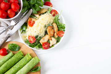 Chicken salad with cheese and tomato , basil,  spinach pancakes, spinach leaves. White wooden board