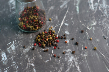 Glass pepper mill with a mixture of peppercorns on a dark background, close-up, horizontal format...
