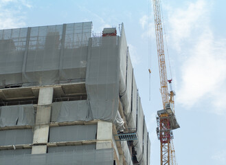 Construction cranes and construction buildings are wrapped in dust-proof canvas and rubble to ensure safety. - 444028814