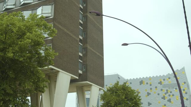 Council flat block with interesting architecture against a grey sky with a new building in the background