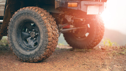 Part of an off-road vehicle on a dirt road with warm light. Adventure concept.Tire off-road on mud 