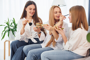 Teaching how to do make up. Young mother with her two daughters at home at daytime