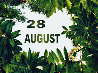 August 28, 28th day of month. Composition of natural green leaves with paper card. Summer month. Concept of Day of Year