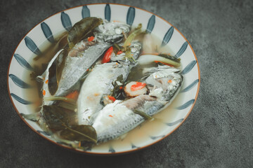 Hot and spicy soup of mackerel fish with chilli and local herbal vegetable in the bowl.