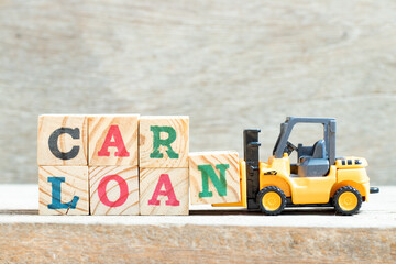 Toy forklift hold letter block n in word car loan on wood background