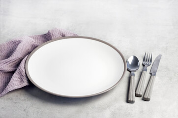 Table setting. White plate, cutlery and napkin.