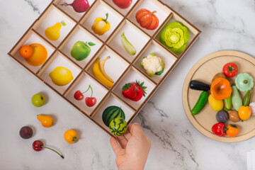 polymer vegetables. sorting by color. studying vegetables. Girl child plays with toy vegetables and buckets of different colors.