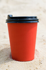 Coffee paper cup on the sand on the beach on a summer sunny day against the backdrop of water