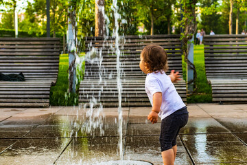 Child playing with garden sprinkler. Kid in bathing suit running and jumping. Kids gardening....