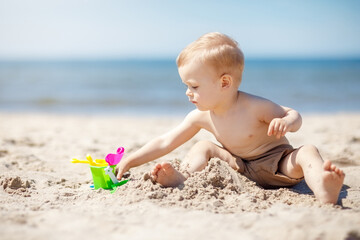 Cute baby boy playing with beach toys
