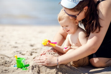 Mother and son on the beach playing with sand.