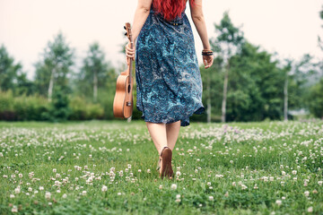 Fototapeta na wymiar young woman goes into the distance, holding a ukulele in her hand