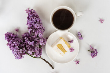 Cup of coffee and cake horns fromstill life with a bouquet of lilacs on a white table, a cup of coffee, a plate with a piece of cake. international Women's Day, March 8