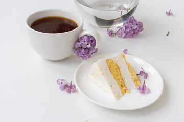 Cup of coffee and cake horns fromstill life with a bouquet of lilacs on a white table, a cup of coffee, a plate with a piece of cake. international Women's Day, March 8