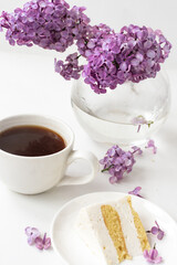 Cup of coffee and cake horns fromstill life with a bouquet of lilacs on a white table, a cup of coffee, a plate with a piece of cake. international Women's Day, March 8