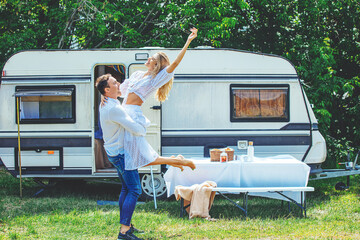 Couple of a beautiful woman in love and a man in nature are relaxing traveling in a trailer, a...