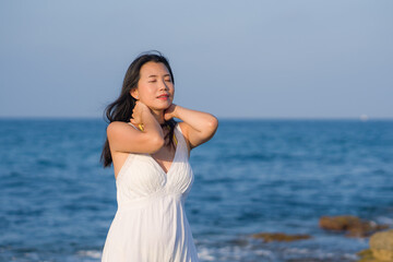 Fototapeta na wymiar summer lifestyle portrait of young beautiful and happy Asian woman at the beach - Attractive Korean girl by the sea enjoying holidays trip on rock cliff with ocean view