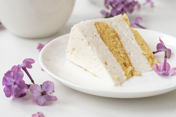 Cup of coffee and cake horns fromstill life with a bouquet of lilacs on a white table, a cup of coffee, a plate with a piece of cake. international Women's Day, March 8
