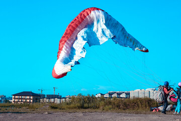 Doubles paragliding landing on the ground. Close-up landing of a multi-colored paraglider