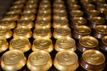 Many aluminum cans stand in a row on a shelf close-up. Tops of aluminum cans closeup in a row on a rack.