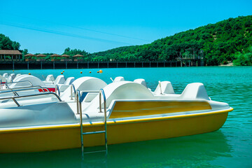 Row of white catamarans standing on the lake. Catamarans near the pier in sunny weather.